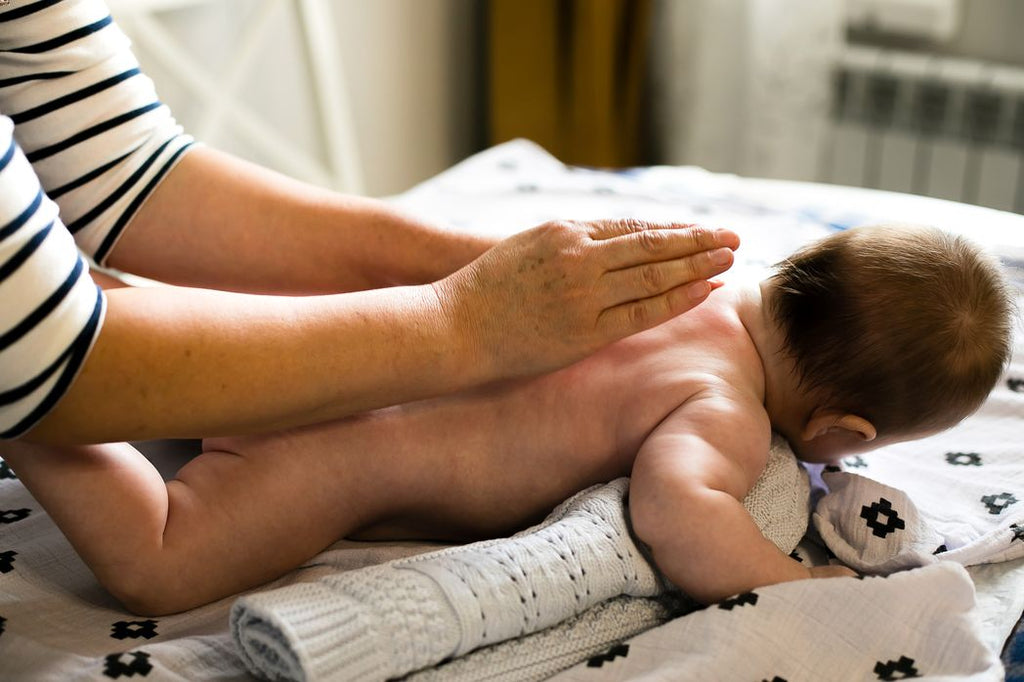 Mother using oil to massage her newborn baby and help them fall asleep