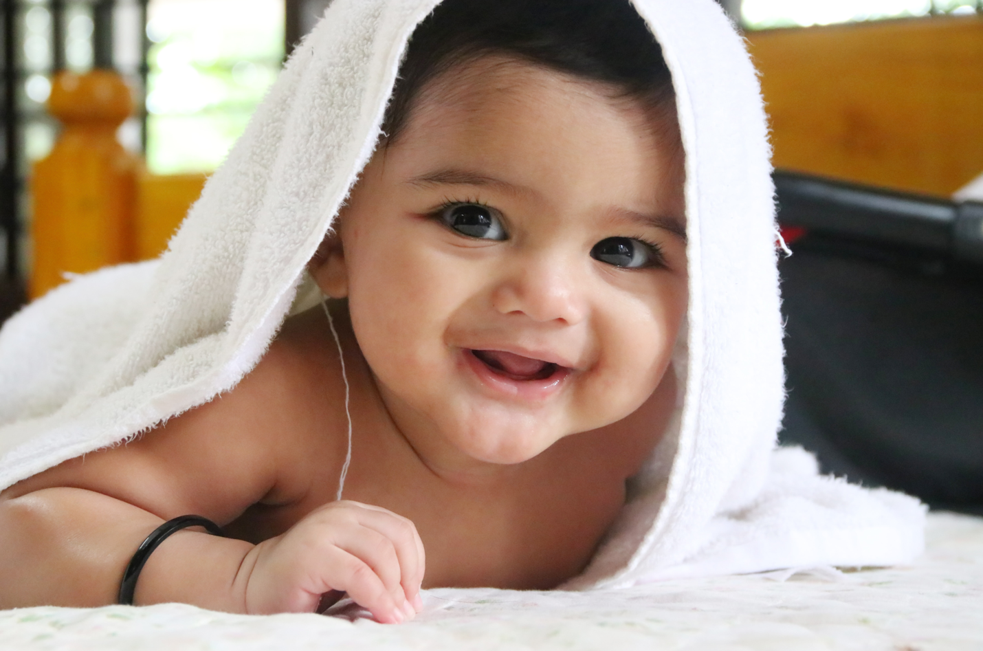 A smiling baby wearing a soft baby towel. Baby towels can be used by adults as well