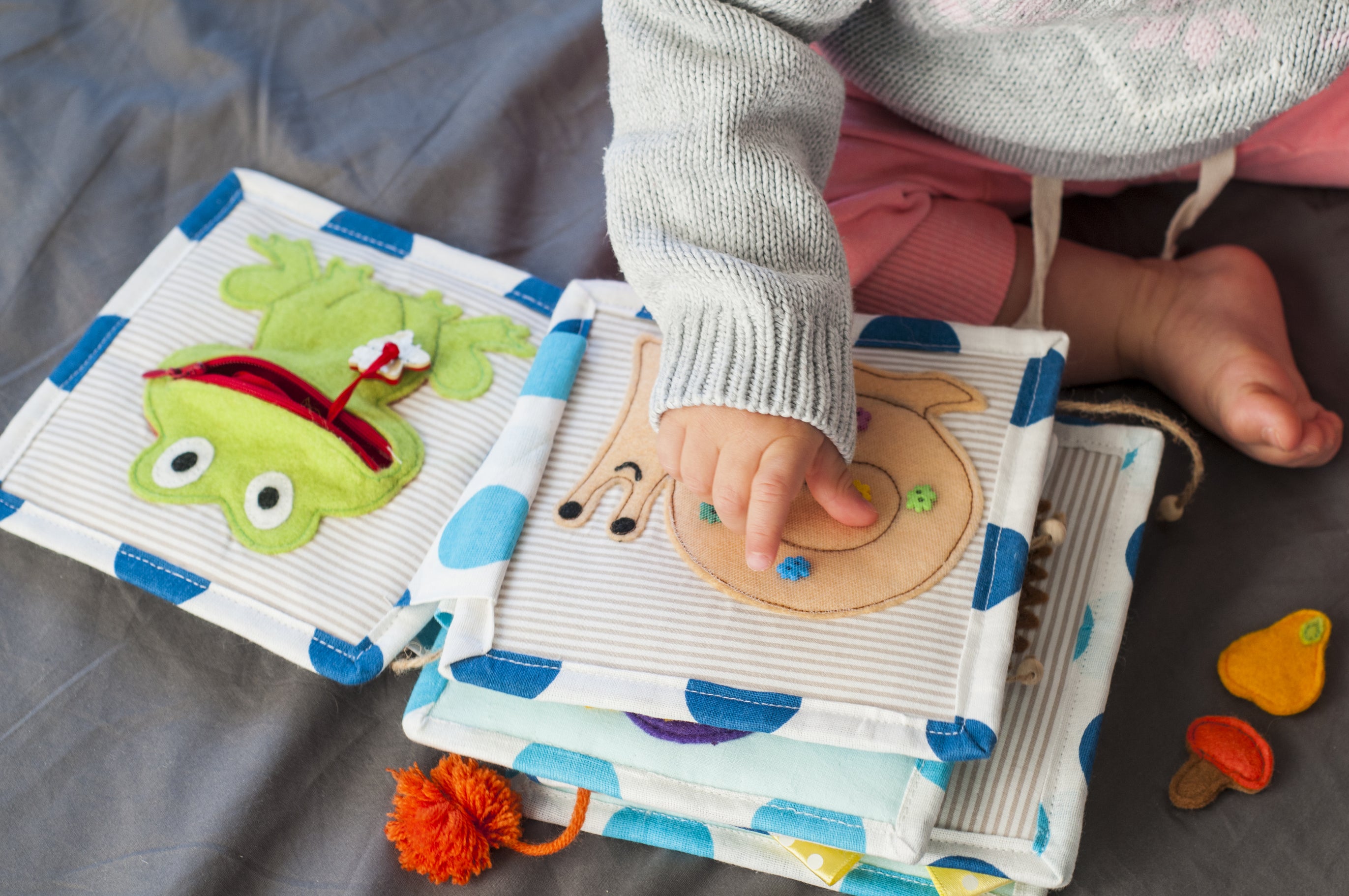 A baby touches and explores a DIY baby felt book with a frog and snail visible on the pages