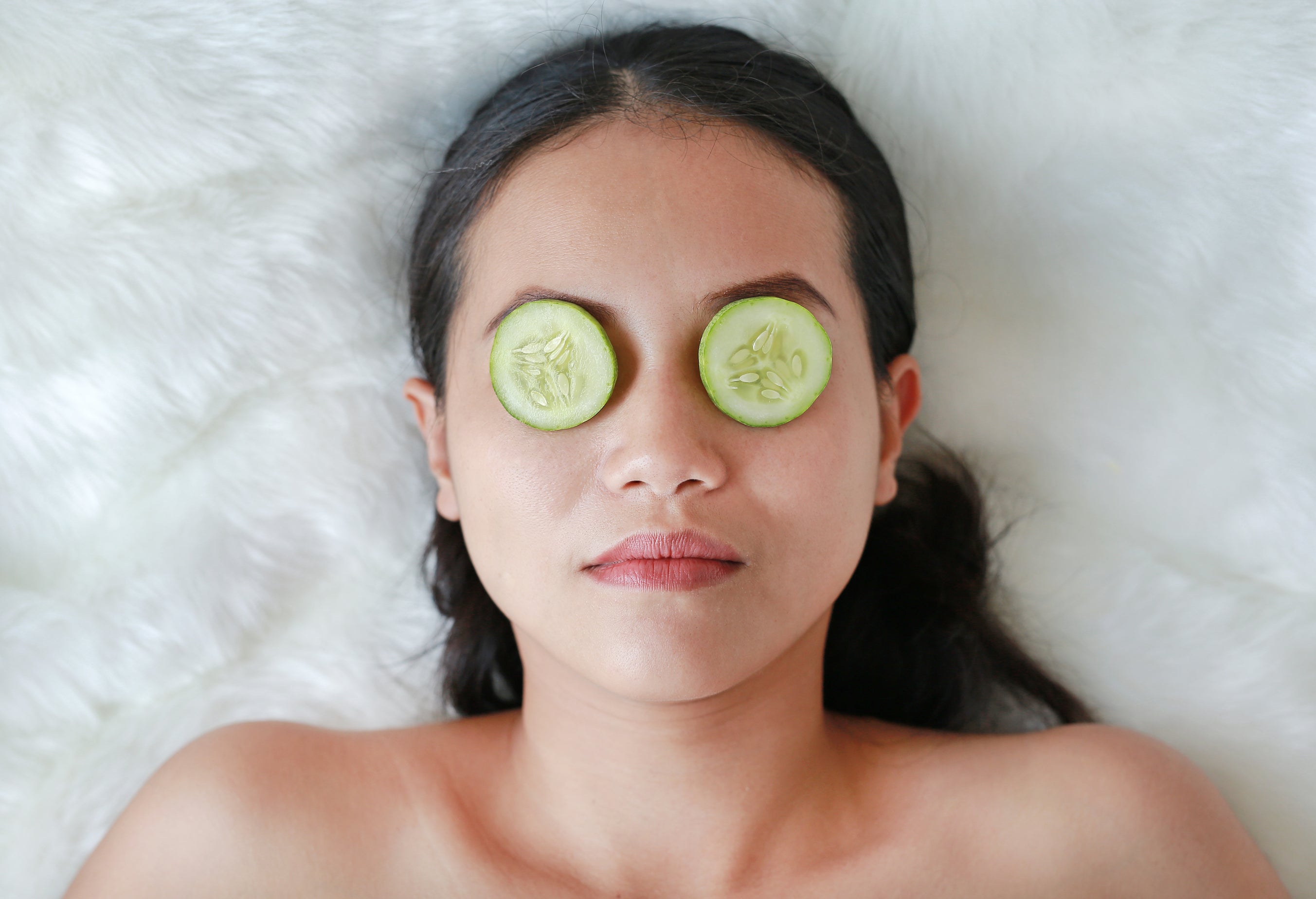 A pregnant woman relaxes her eyes and nourishes her undereye region by applying cool cucumber slices 