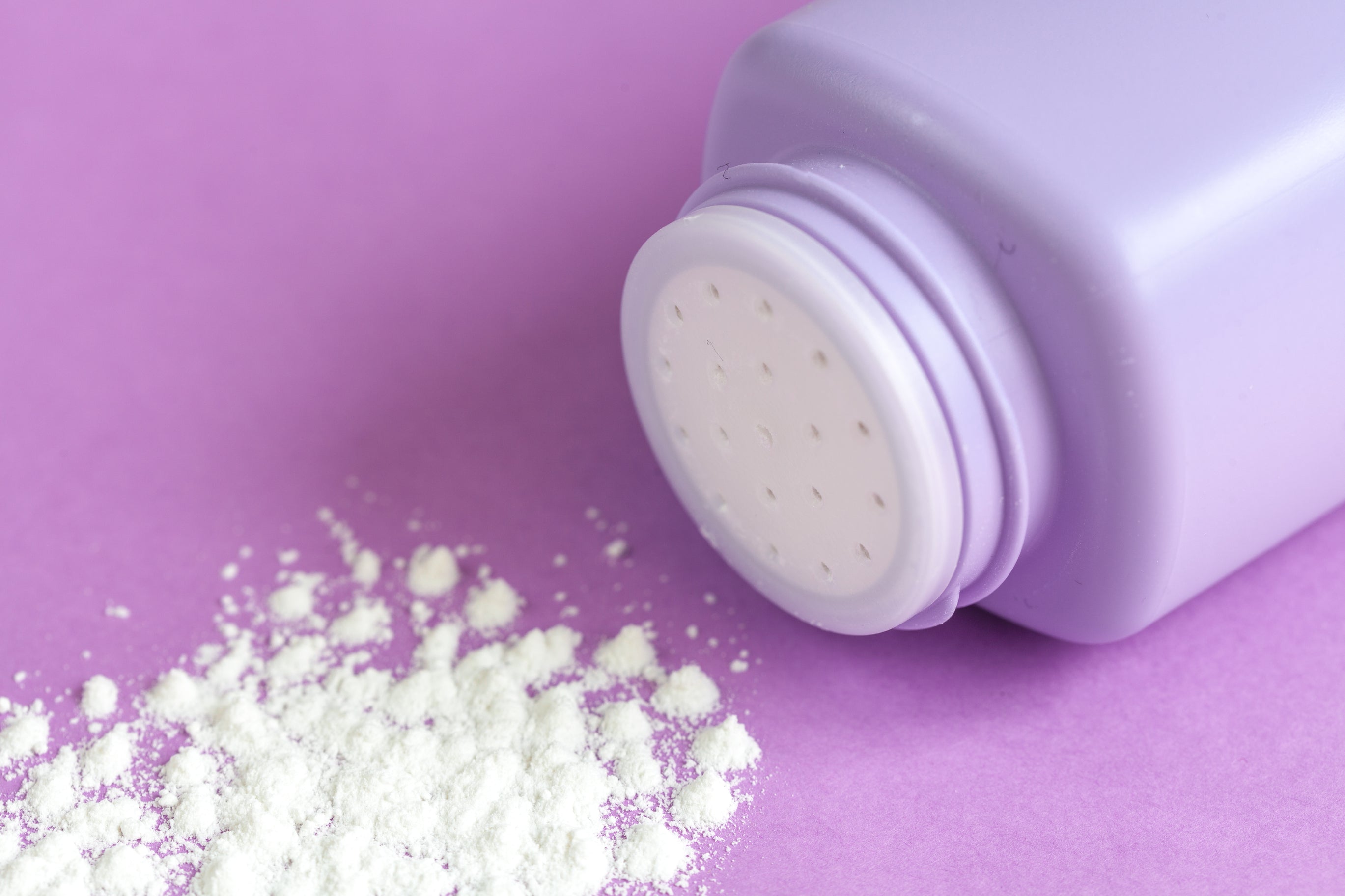 Talcum powder bottle against a lavender background. Baby talcum powder, talc, talc-free, asbestos, cancer.