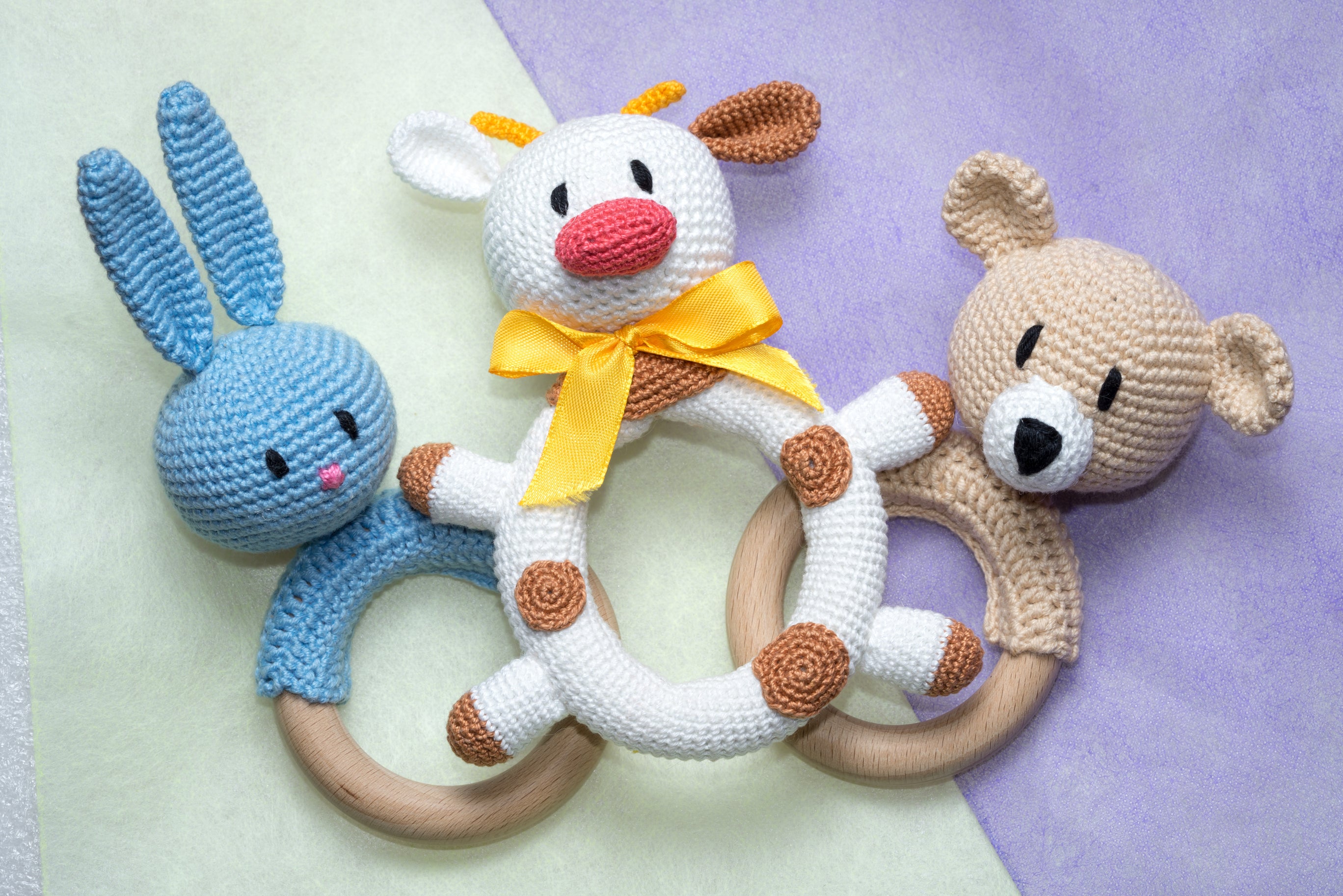 Three home made crochet or amigurumi baby rattle in the shape of a rabbit, bull, and bear 