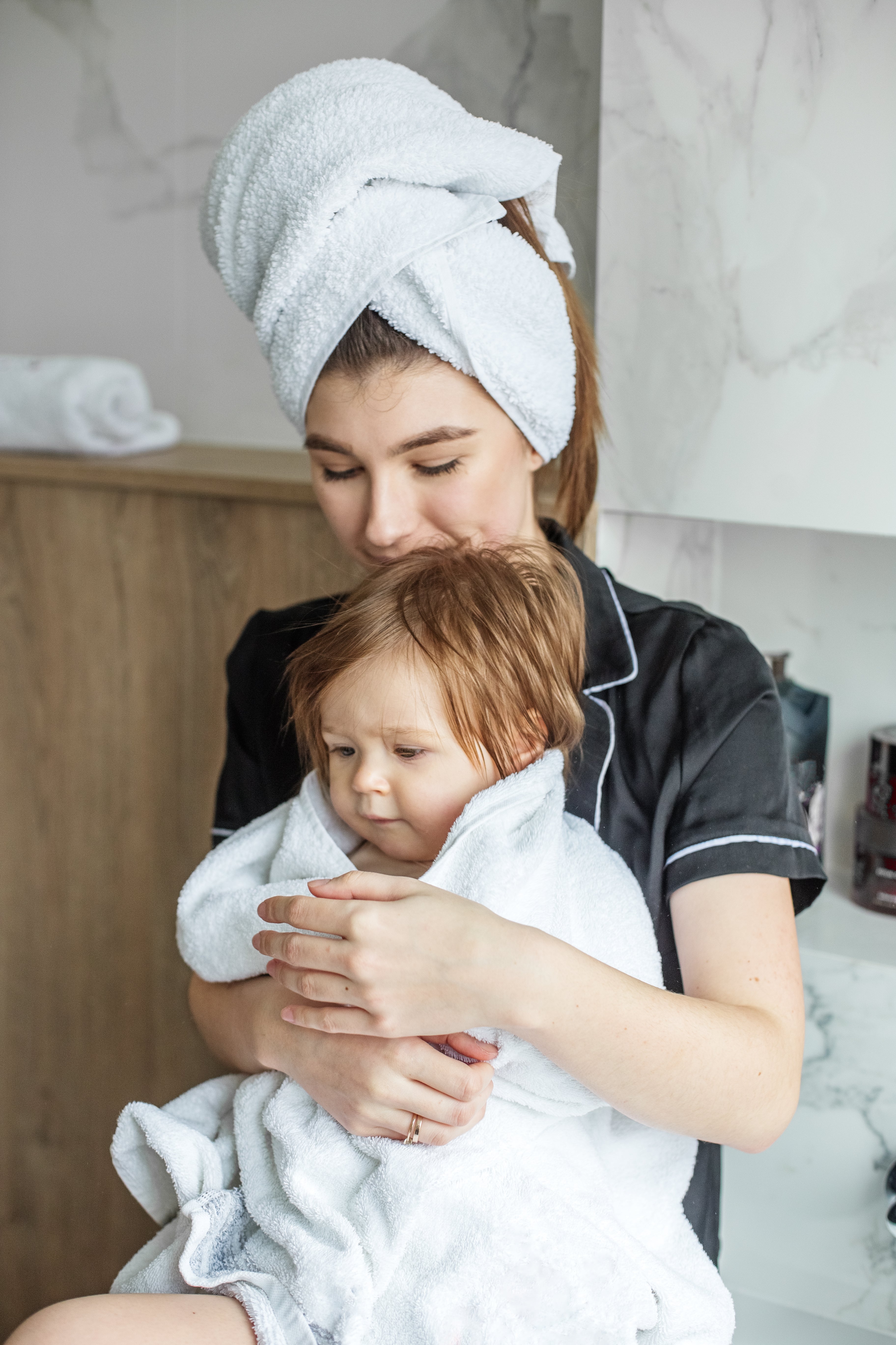A mother and baby wrapped in towels and standing in the bathroom, ready for steam inhalation 