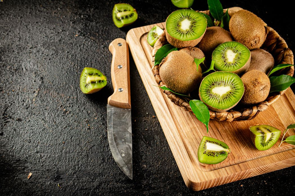 Sliced kiwis in a basket along with a knife and a chopping board. Healthy halloween snack for toddlers.