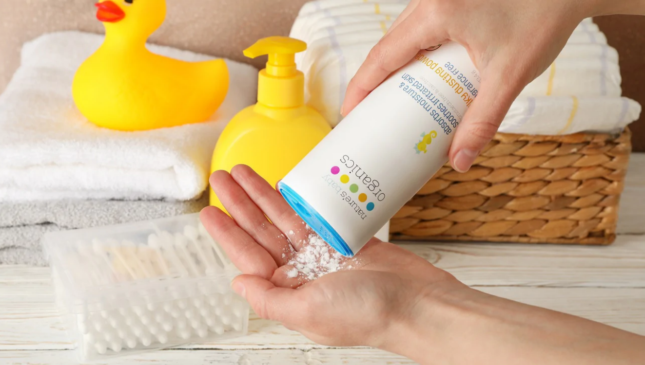 A hand holding Nature's Baby Organics Organic Silky Baby Powder Fragrance Free. Baby powder can be used by adults as well. 