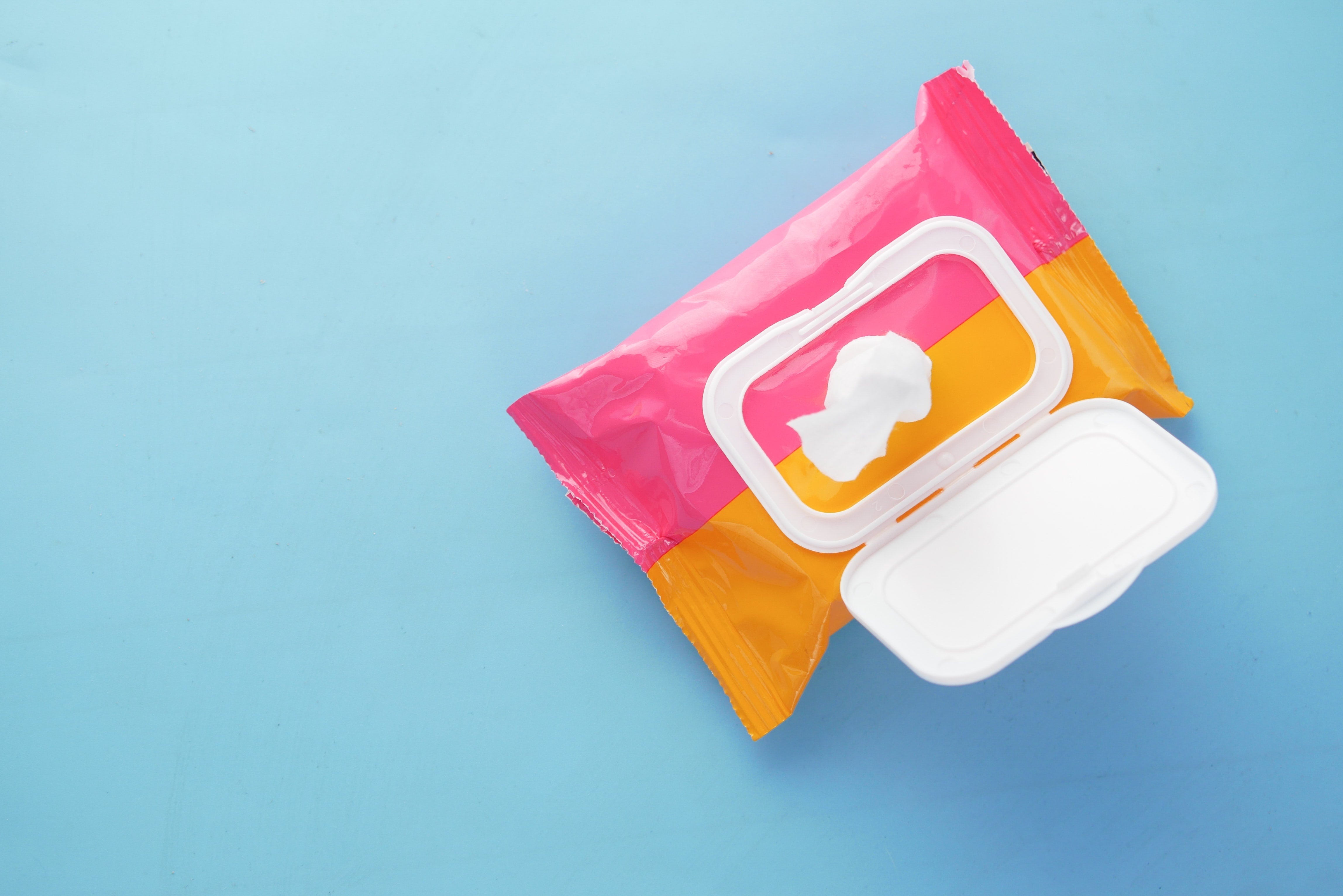 An open pack of baby wipes against a blue surface. Baby wipes can be useful for adults also.