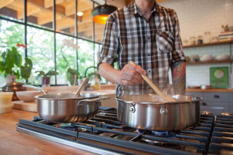 uomo che cucina con l'acciaio inossidabile