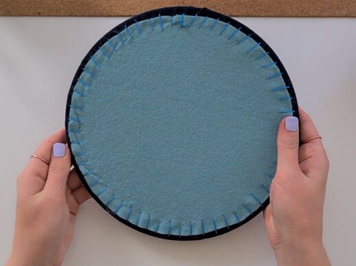 The reverse of an embroidery hoop backed with teal felt