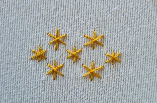 Six embroidered yellow stars on white fabric background