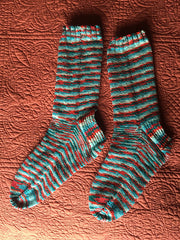 Two finished, striped socks in teal and red.