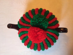 top of a red and green tea cosy showing red and green pompoms on the top