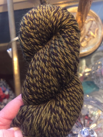 Handspun skein of 3-ply yarn. One ply brown, two plies olive green