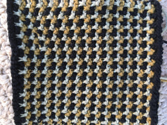 Handknit dish cloth in tan, gold, and black checked pattern.