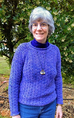 Amy smiling as she wears a periwinkle crocheted sweater