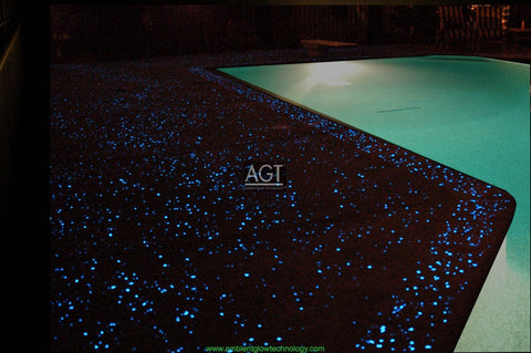 Glowing concrete pool deck Powered by AGT™ Commercial-Grade 1/2" Glow Stone in Sky Blue & Aqua Blue, close up during the night.