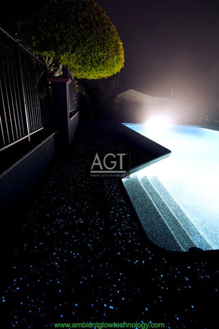 Glowing concrete pool deck Powered by AGT™ Commercial-Grade 1/2" Glow Stone in Sky Blue & Aqua Blue, full view during the night.