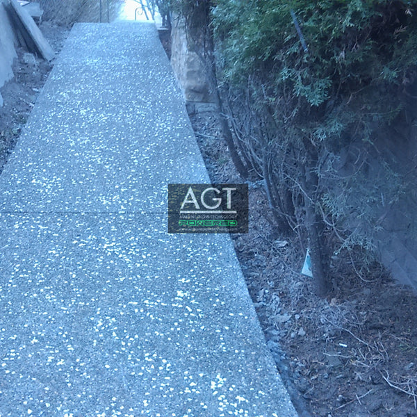 Concrete walkway powered by 1/2" (12-14mm) AGT™ Commercial-Grade Glow in the dark gravel in Aqua Blue and Emerald Yellow glow colors. Day time.