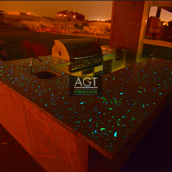 Glowing concrete decorative wall and outdoor kitchen island powered by AGT™ Commercial-Grade Glow Stone in Emerald Yellow and Aqua Blue 1/2" shown at night top angle
