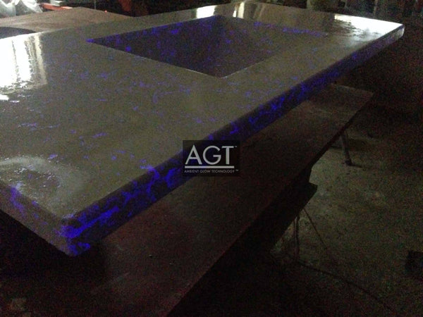 Close up view of a glowing concrete bathroom vanity using AGT™ Plasma Purple Fine Glow Sand.