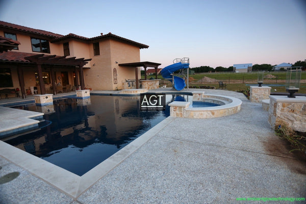 Glowing concrete pool deck in Texas, powered by 1/2" AGT Commercial-Grade Glow Stones in Sky Blue with accents of 1/2" Aqua Blue glow rocks.