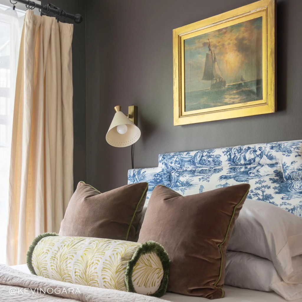 Toile bed in a brown painted room with brown velvet pillows and chartreuse botanical custom pillows and white curtains hanging on the windows