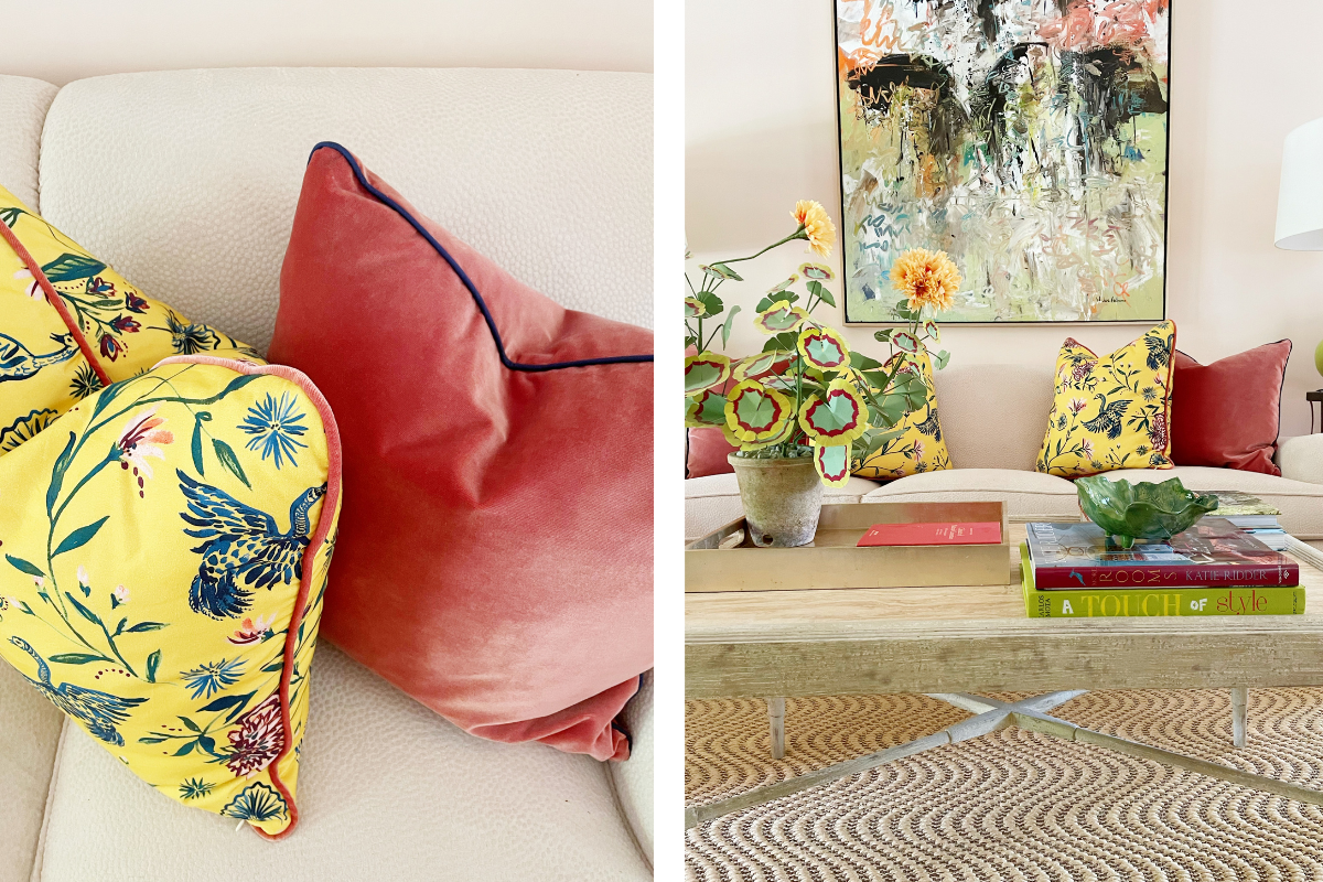 White couch styled with a Coral Velvet custom pillow and a Yellow Chinoiserie custom pillow on each side in a living room next to a coffee table with a green and red plant and books