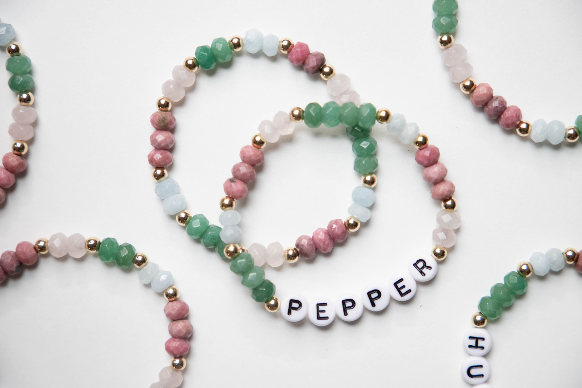 Green white and pink beaded bracelets on a white background
