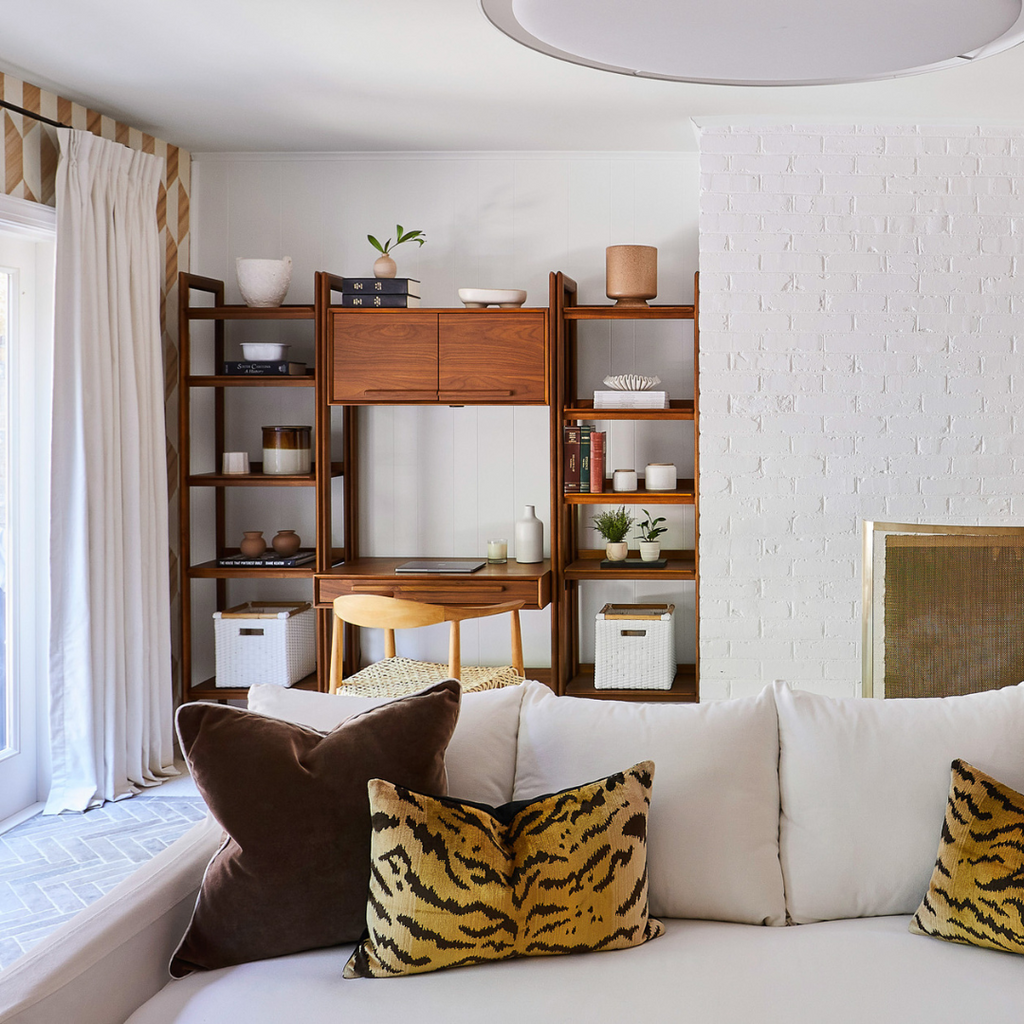 Bright white living room with white couch and brown velvet pillows styled with white custom curtains hanging on a rod in front of a window