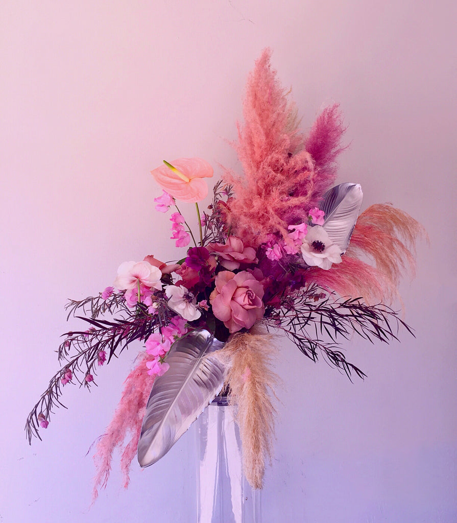 Whimsical pink, purple, and red bouquet in front of a pink and purple backdrop