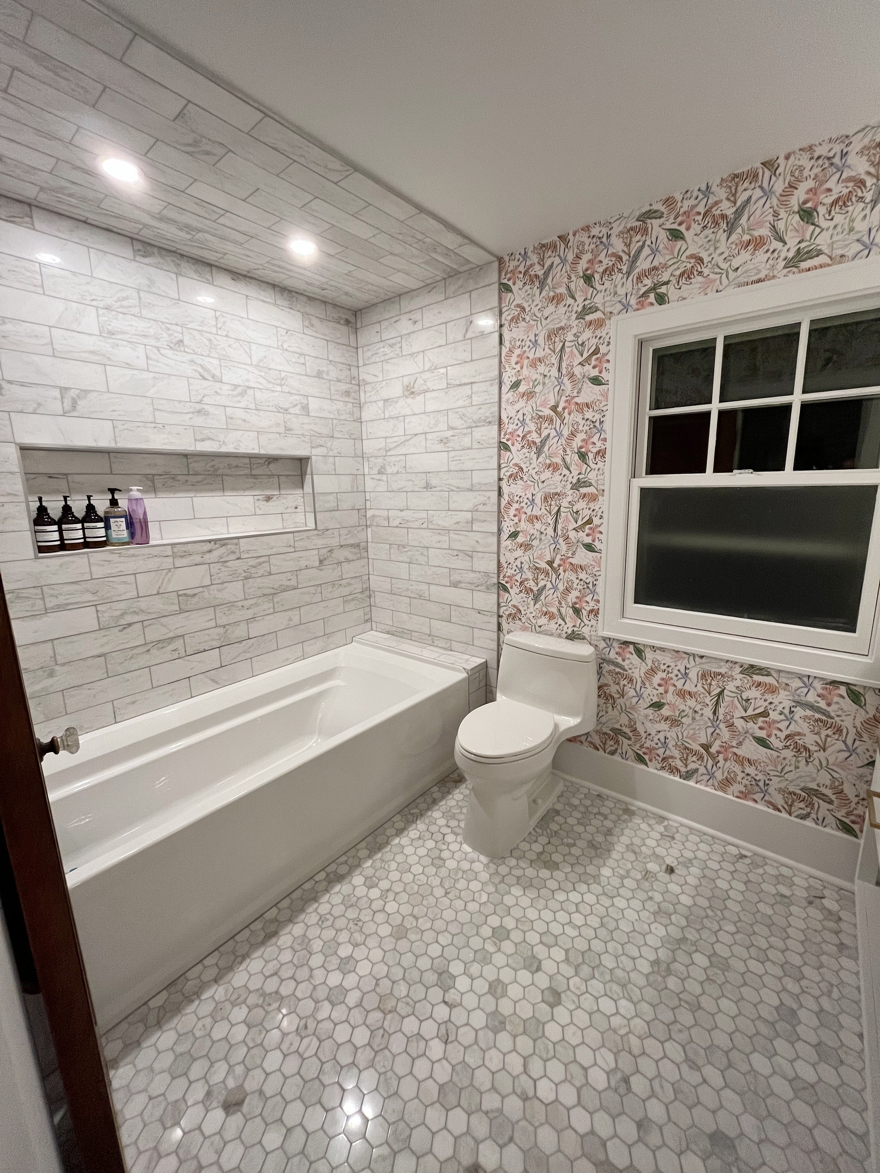 Bathroom with pink chinoiserie tiger wallpaper and large shower tub combo with white tiles