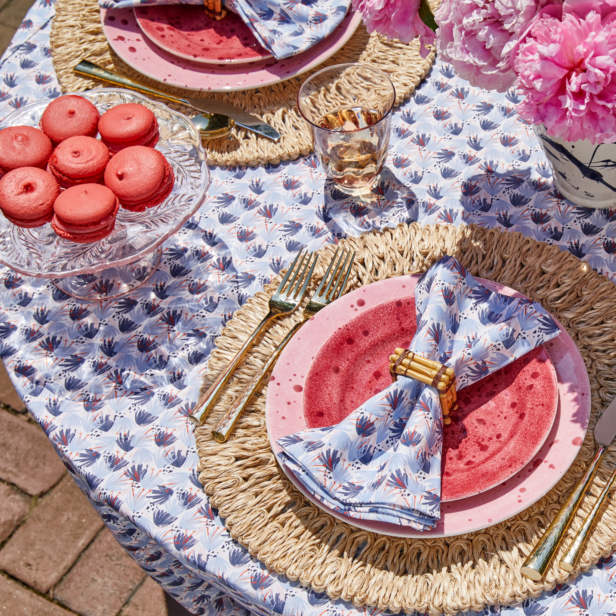 Sky Blue Pattern custom Tablecloth styled with gold silverware and red and blue custom napkins on top of red and pink plates by seven red macaroons on clear plate