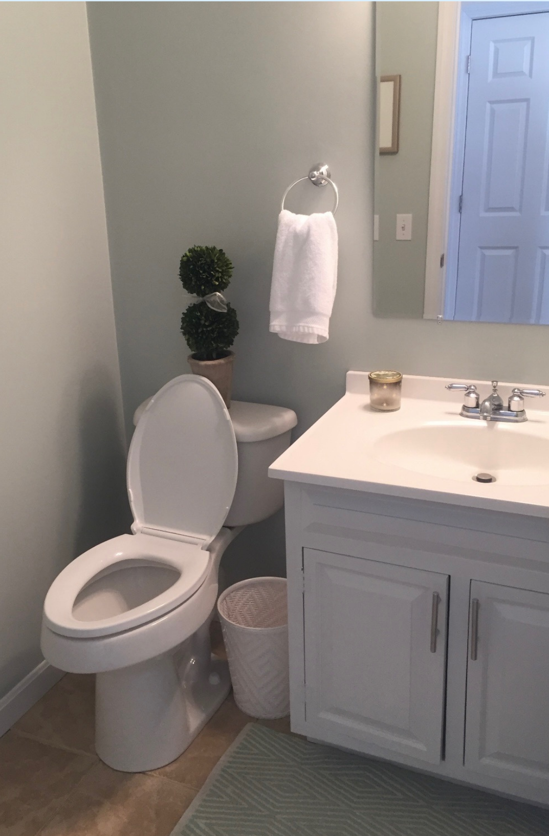 Corner of a bathroom with white toilet, white vanity and white walls