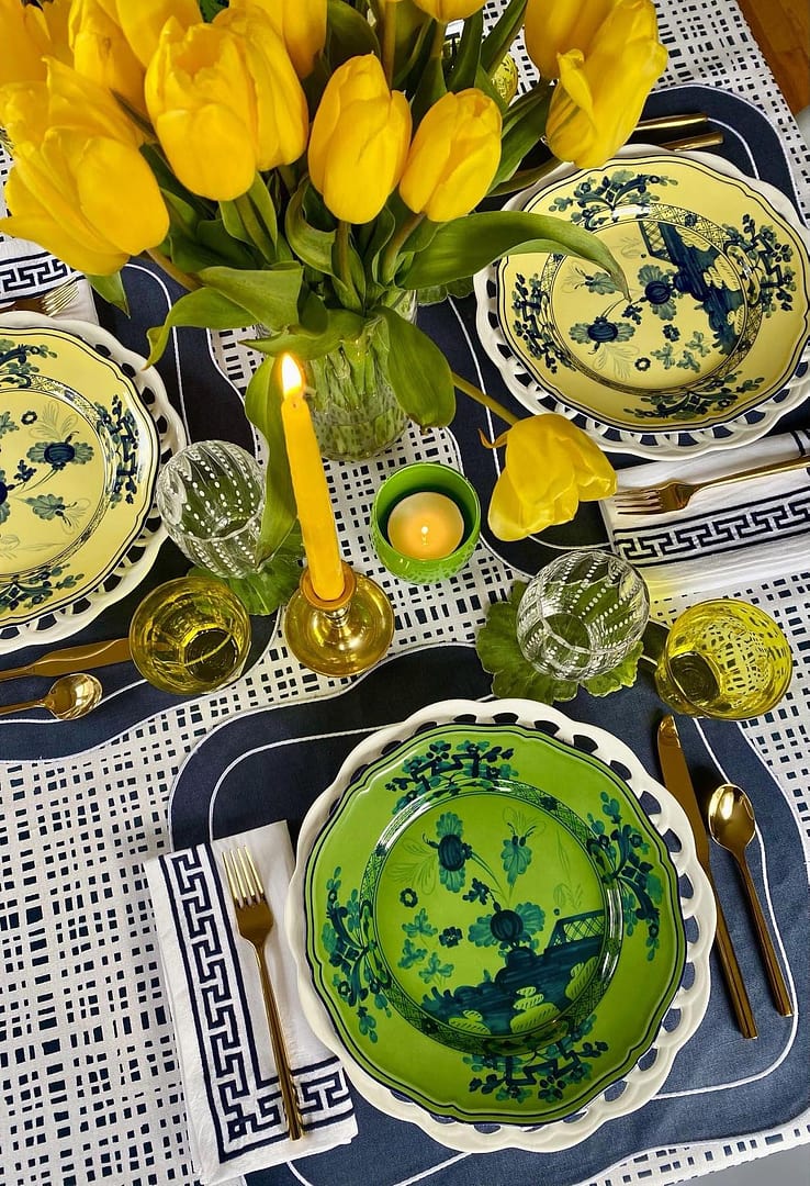Dining table close-up styled with a navy plaid custom tablecloth and yellow flowers in the center for decoration