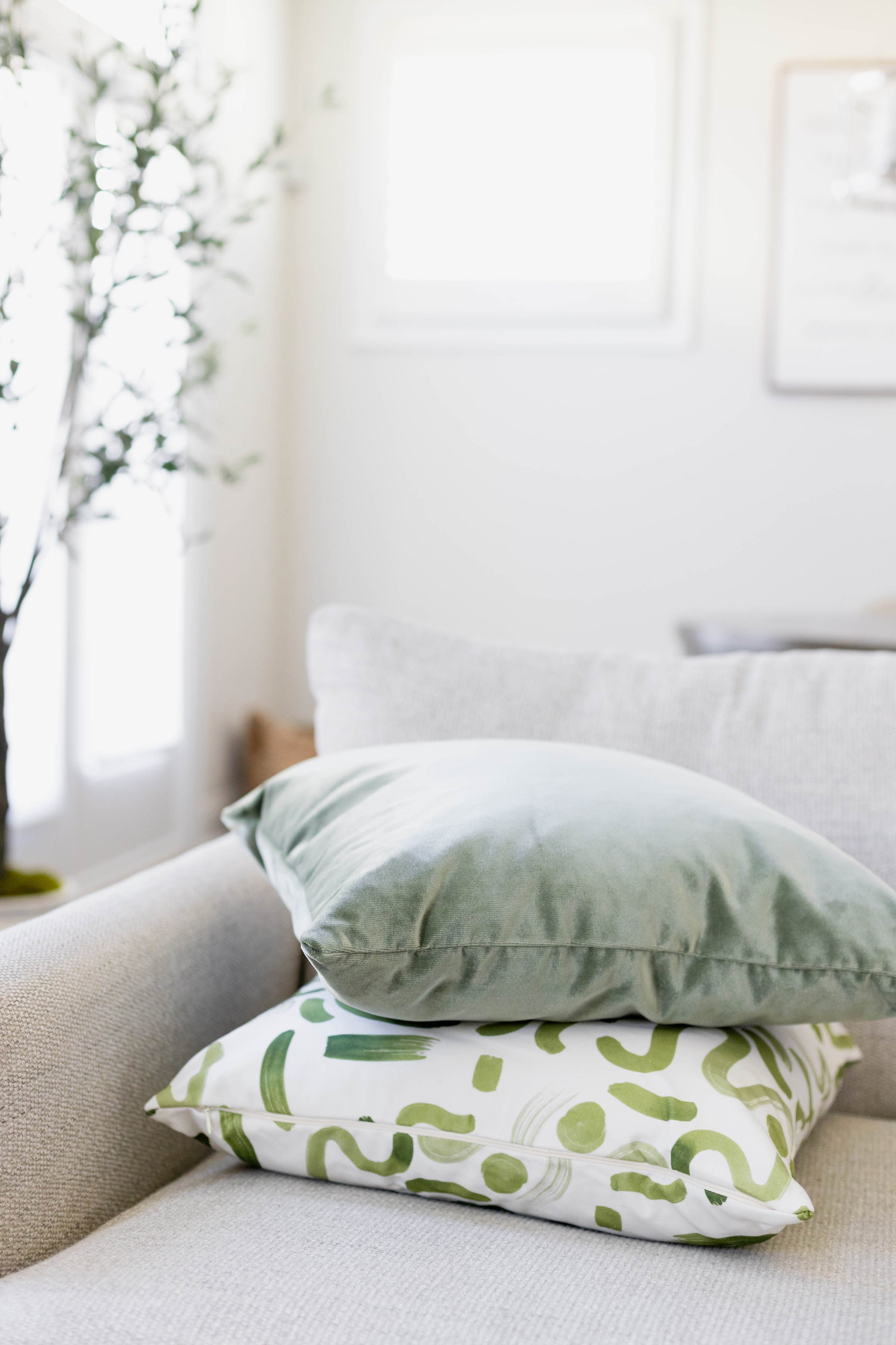 Living room couch close-up styled with a Fern Green Velvet Custom Pillow stacked on a Moss Green Custom Pillow