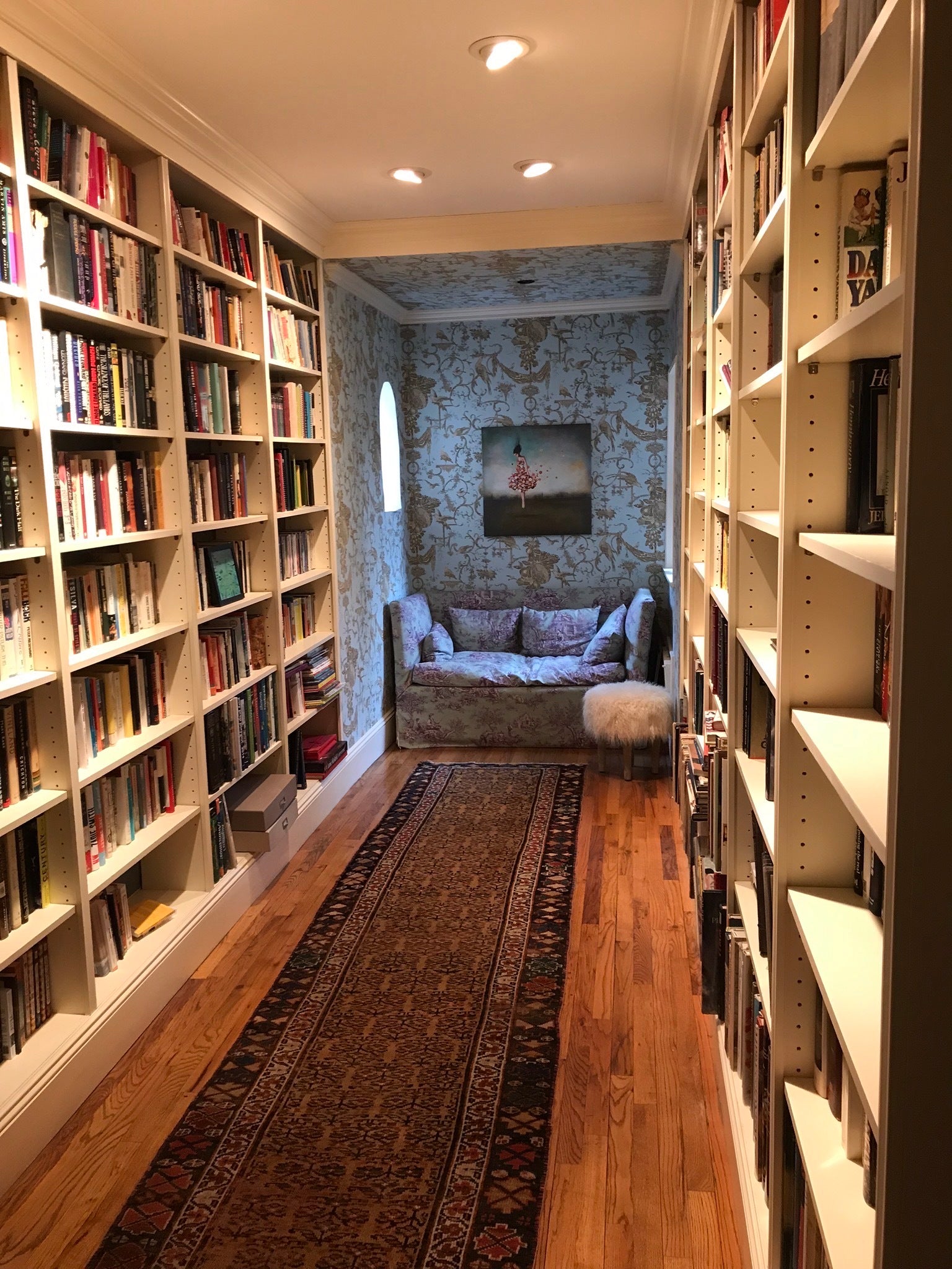 Hallway with bookshelves and floral blue wallpaper