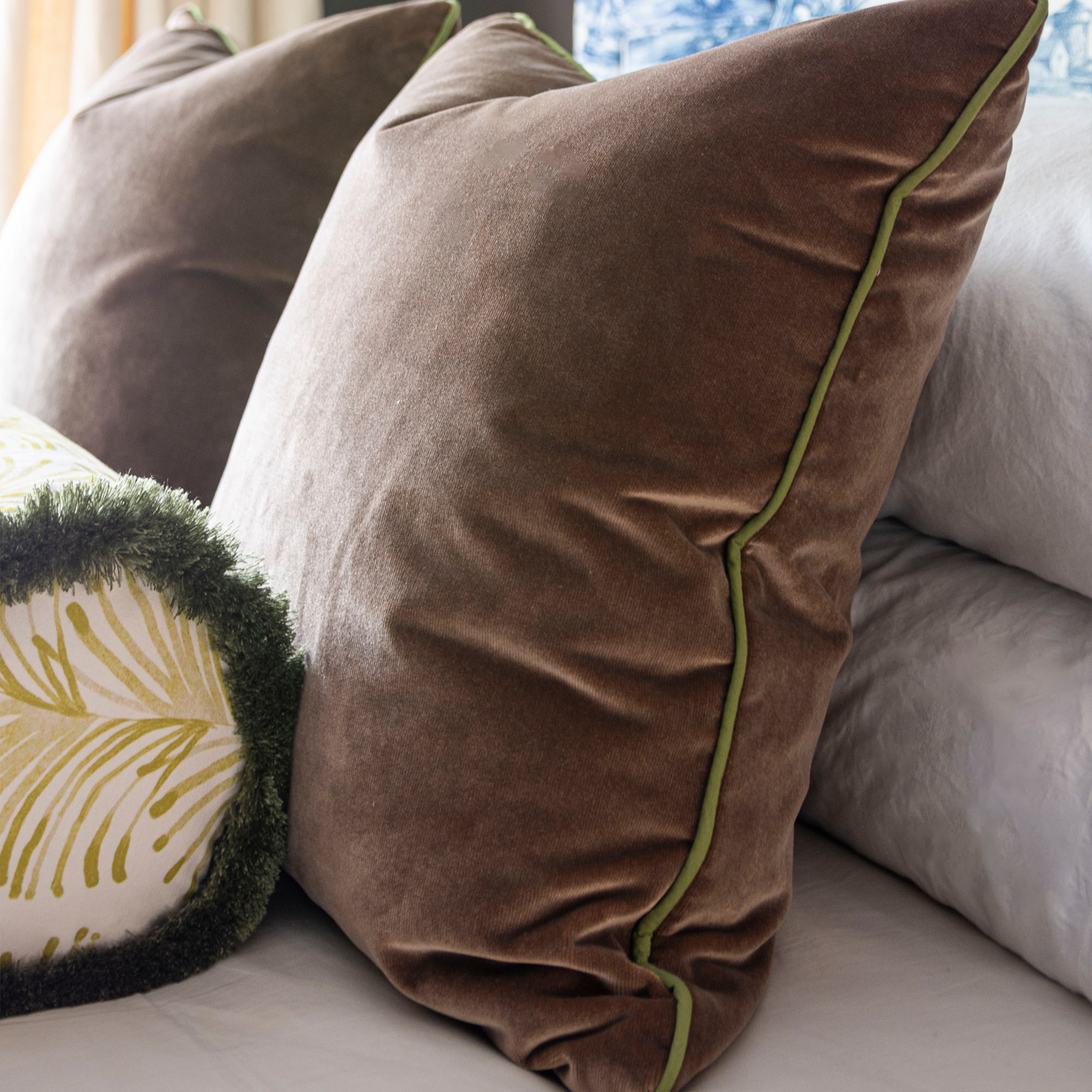 Close-up of two brown velvet custom pillows and one yellow tripe chartreuse custom bolster pillow