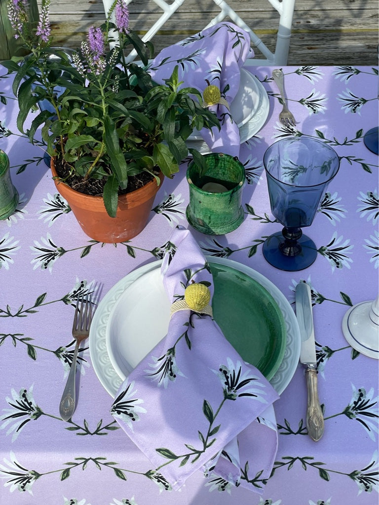 Table styled with botanical lavender custom tablecloth and napkins with lavender plants in clay pot in the center for decoration