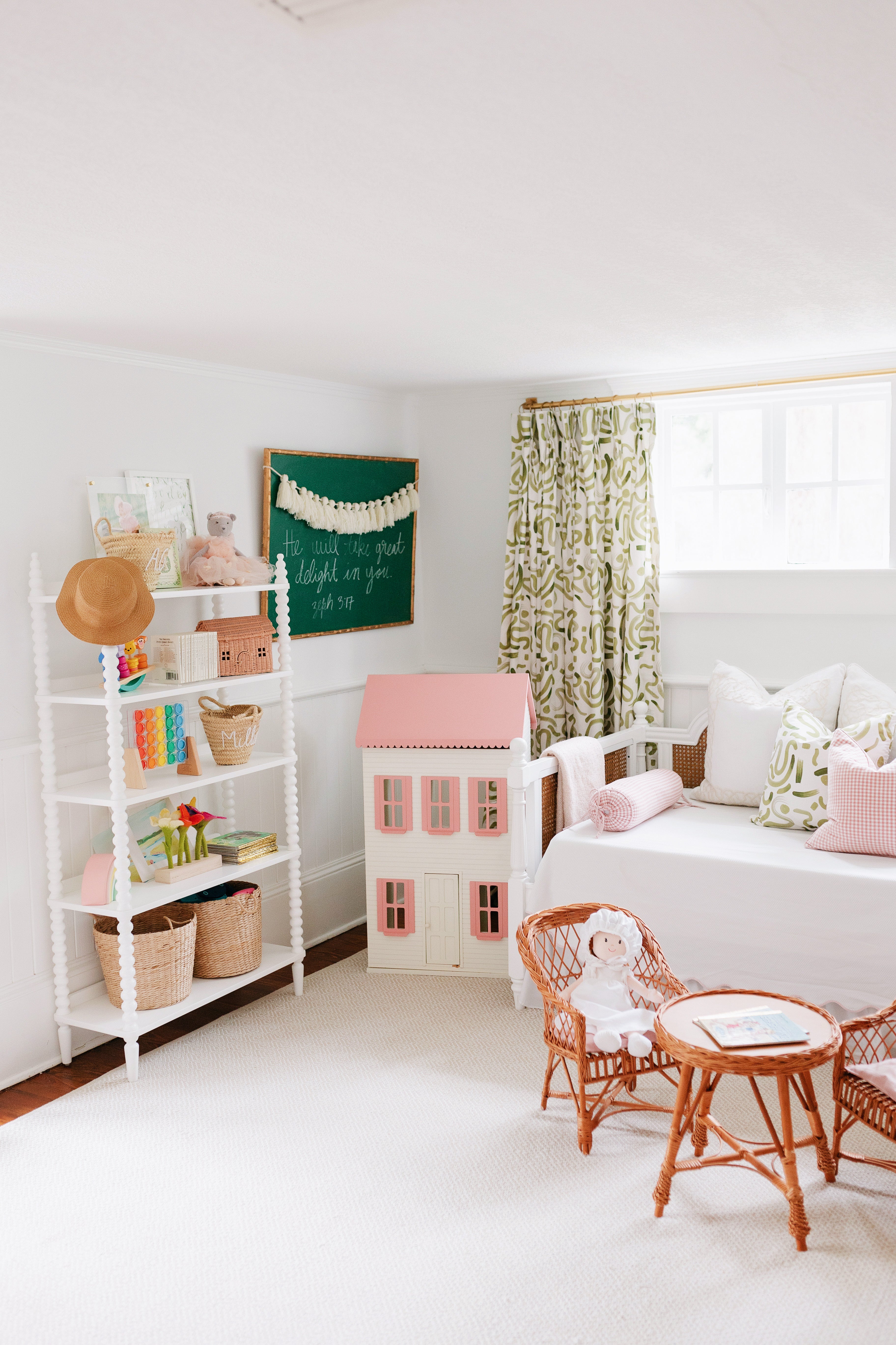 Moss abstract curtain panels hanging on a rod behind a white day bed in a. nursery with a pink gingham tent and rattan kid's furniture