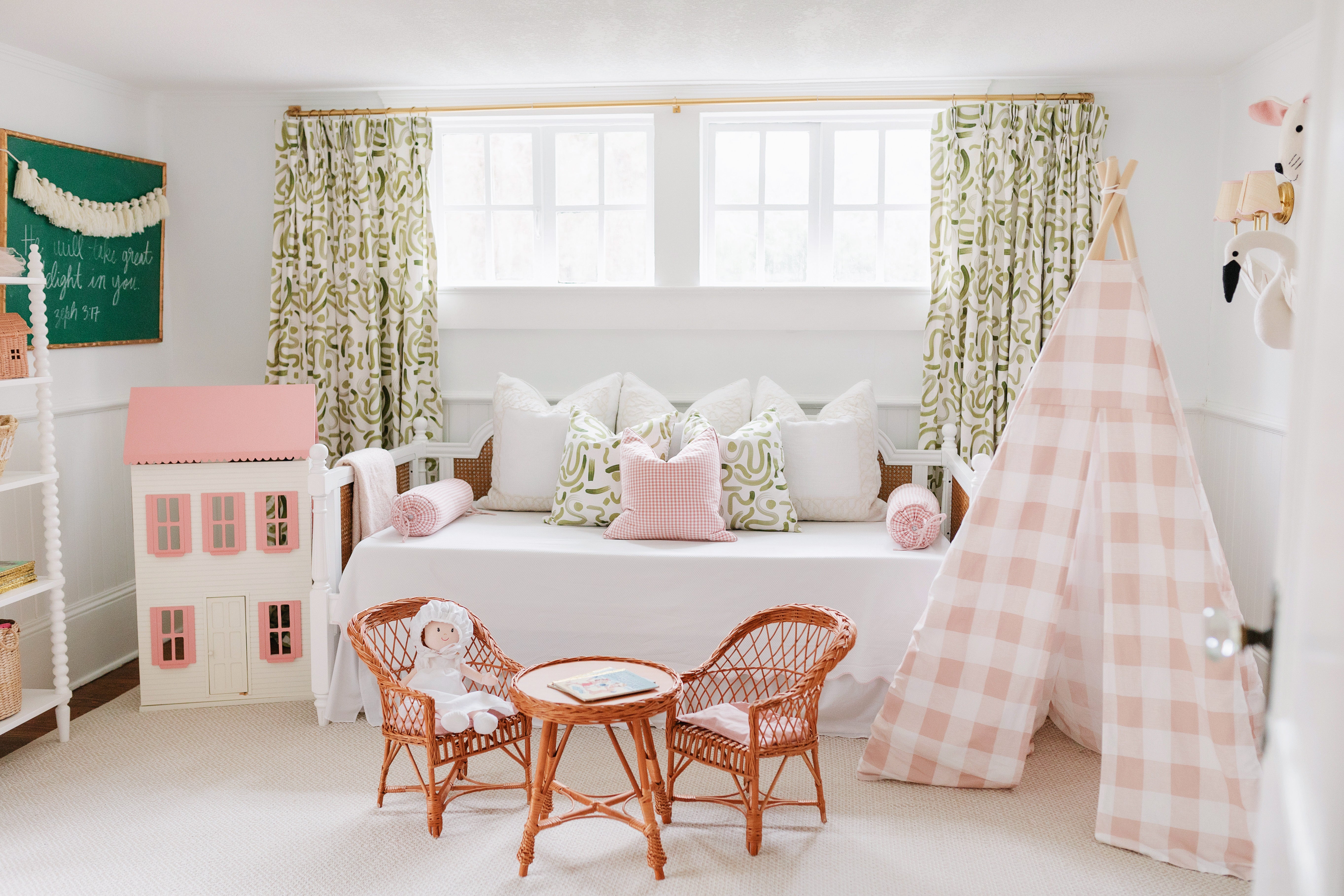 Moss abstract curtain panels hanging on a rod behind a white day bed in a. nursery with a pink gingham tent and rattan kid's furniture