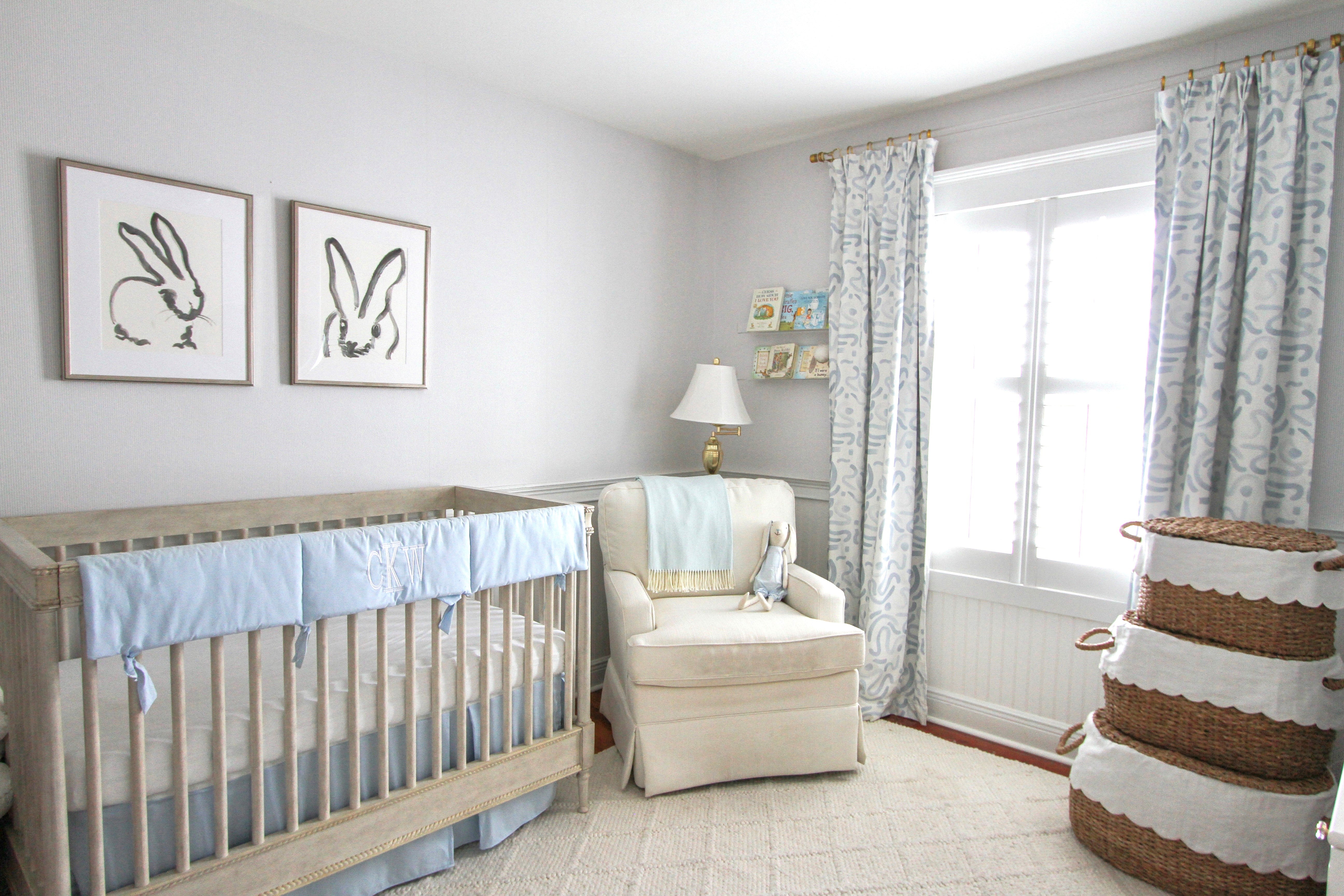 Blue abstract custom curtain hanging on a window in a nursery with a white glider and white crib with rabbit artwork