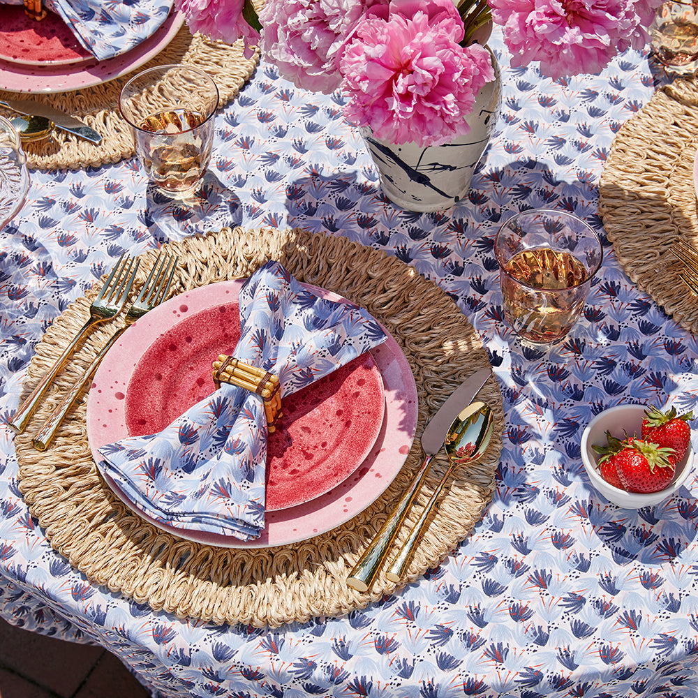 Close up of blue and pink floral tablecloth styled with pink and red plates and blue and red floral napkins