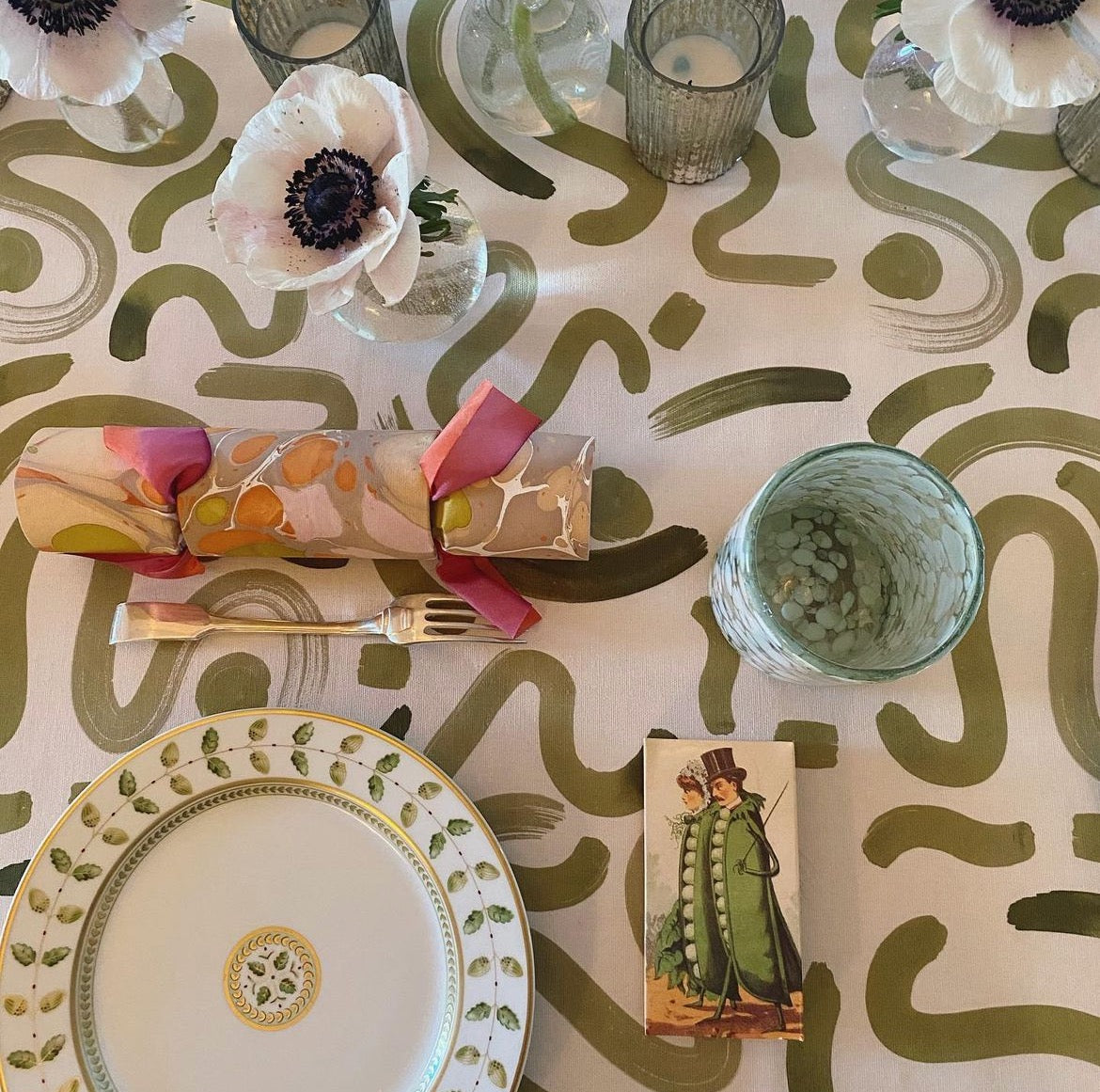Dining table close-up styled with a Moss Green custom tablecloth and white individual flowers as decorations