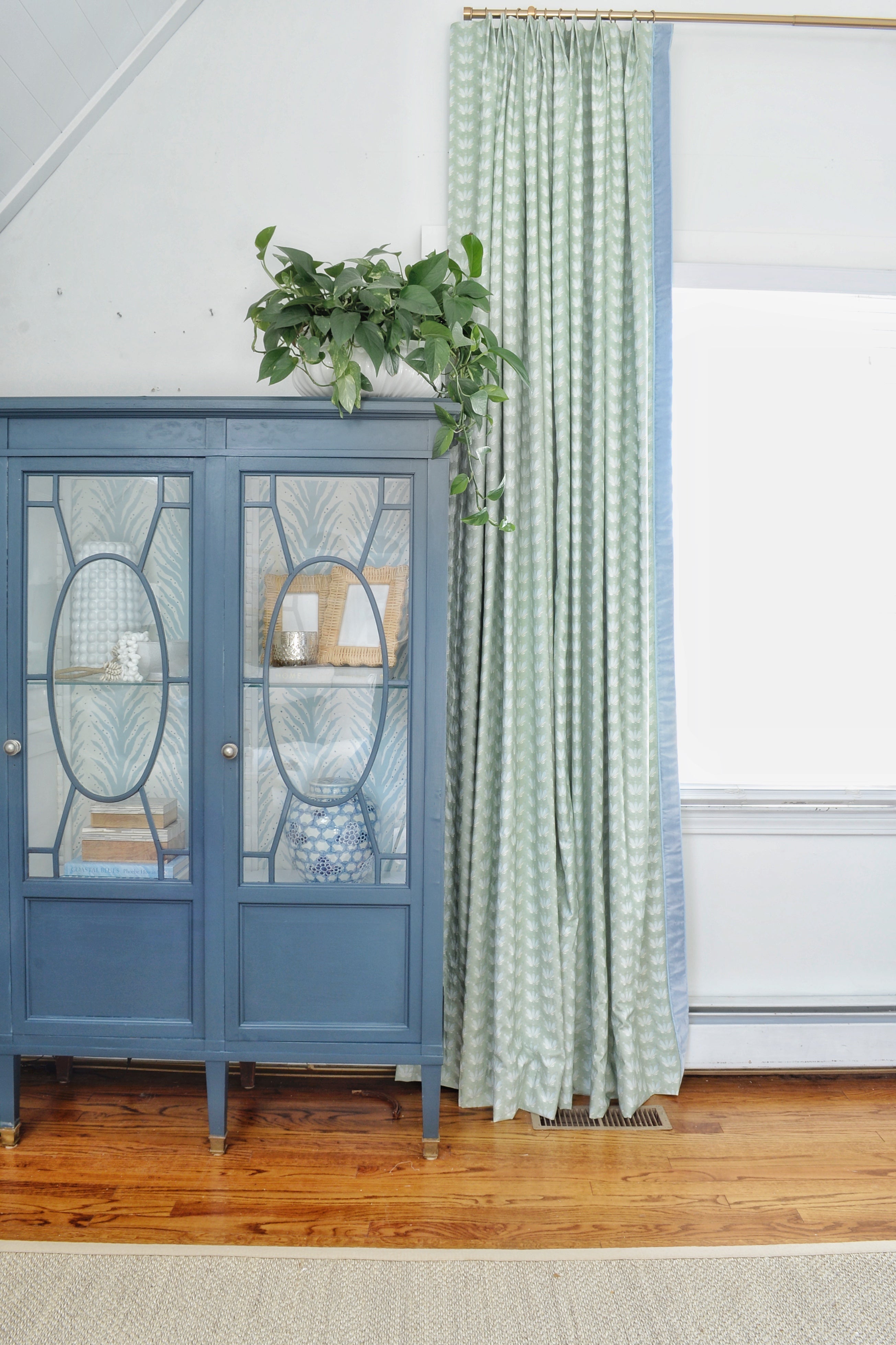 Close-up of Coastal Inspired Green and Blue custom curtain next to a blue wooden cabinet
