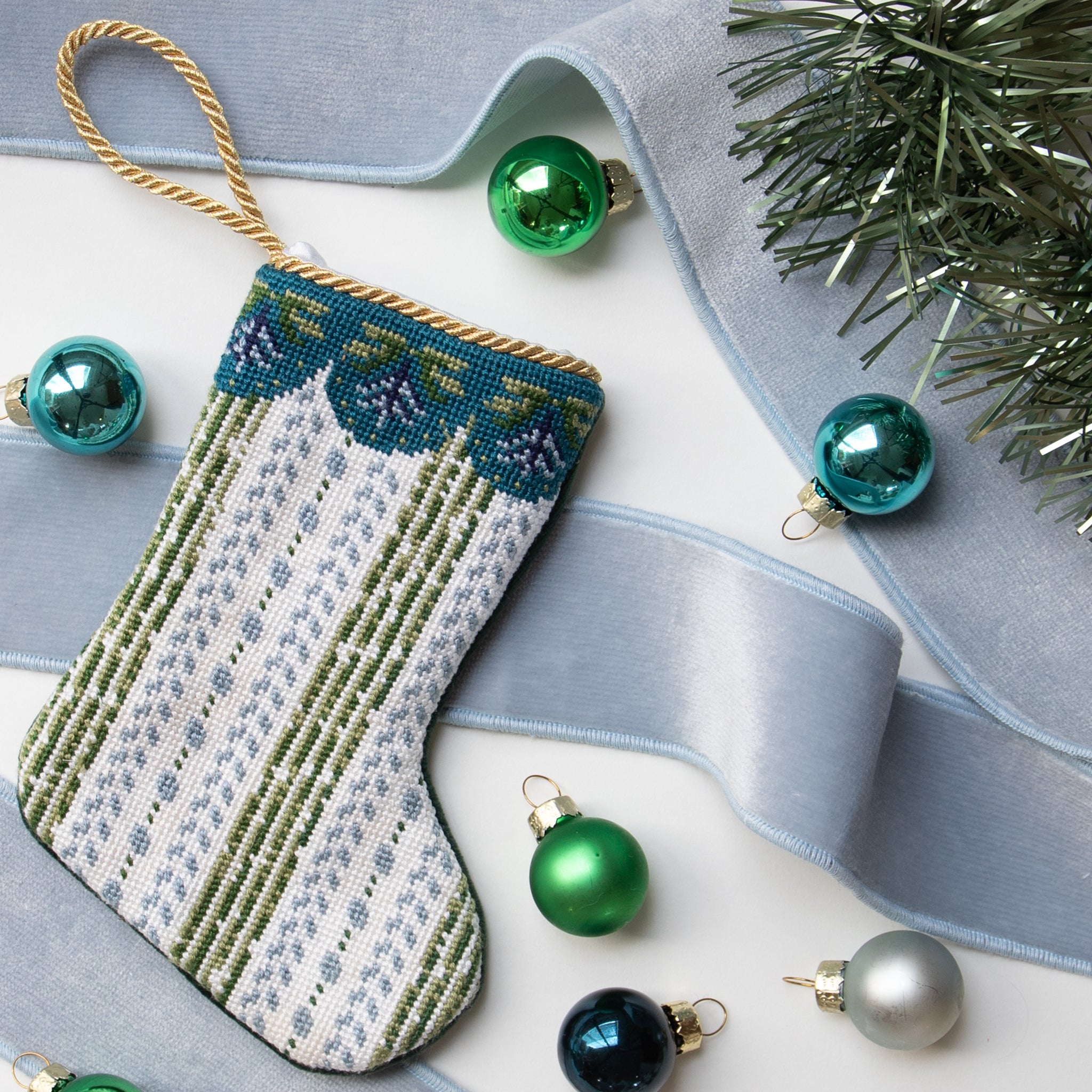 Mini blue and green striped stocking ornament styled with blue velvet fabric trim and mini ball ornaments