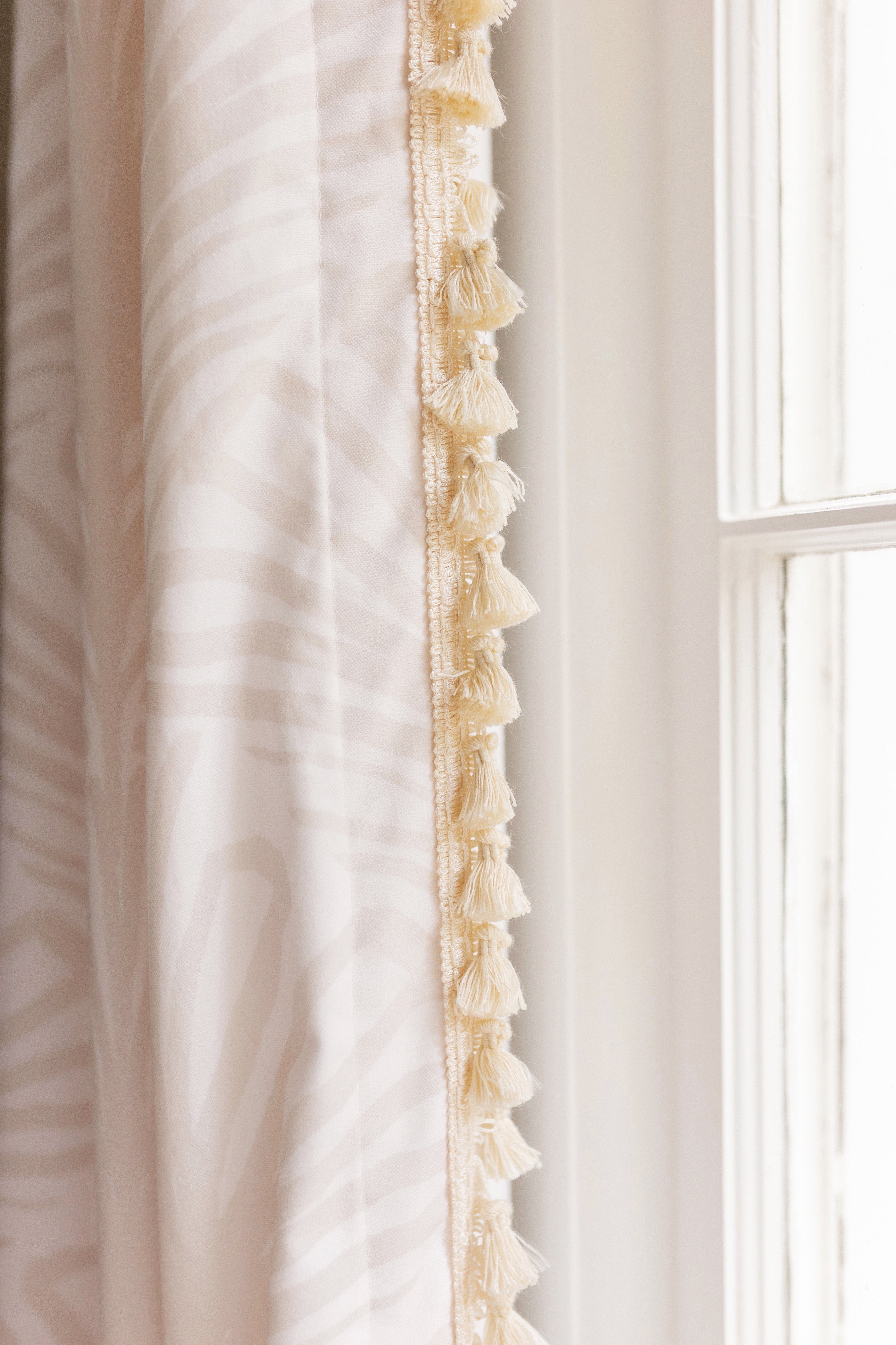 Close-up of beige palm custom curtain with a cream tassel trim