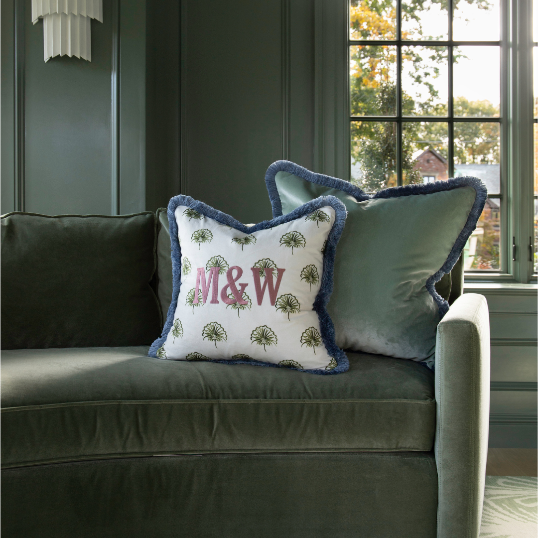 green floral pillow embroidered with "M & W" on green velvet couch in a green room