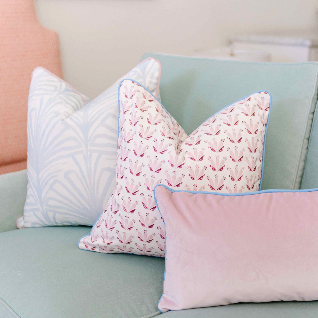 Close-up of Sky Blue Palm Custom Pillow, Pink & Burgundy Drop Repeat Floral Custom Pillow, and Pink Velvet Custom Lumbar Pillow on a Blue Green Couch