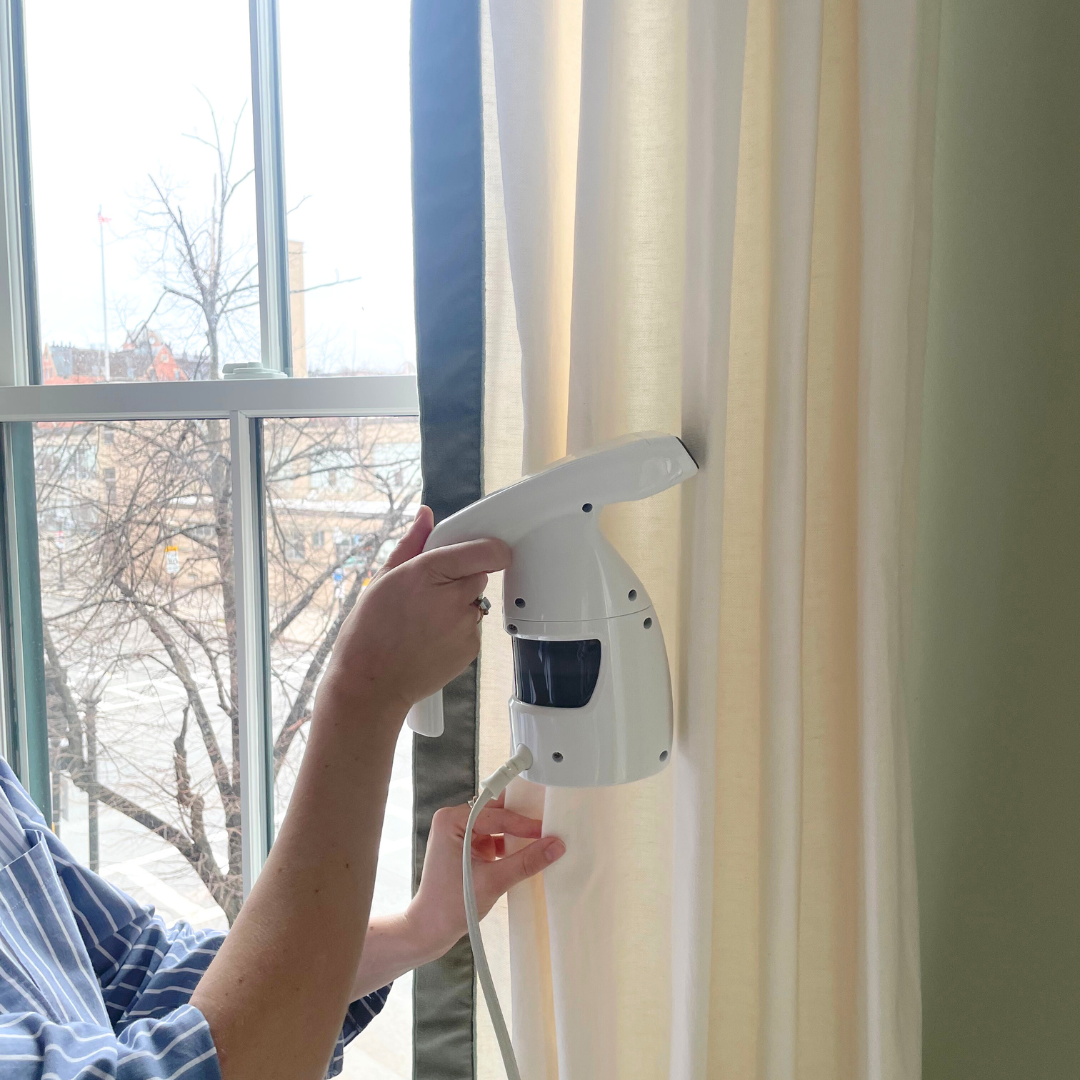 Close up of someone steaming a natural white curtain panel with a green velvet band