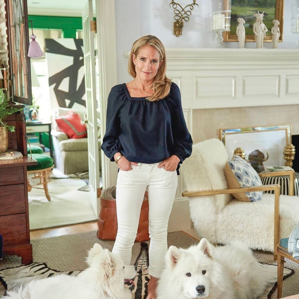 Blonde woman standing in her living room next to her two white dogs