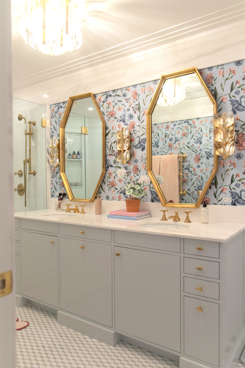 Bathroom with blue chinoiserie wallpaper, gold mirrors and a light blue vanity with brass fixtures